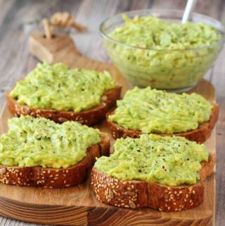 Slices of toast with avocado on a wooden board.