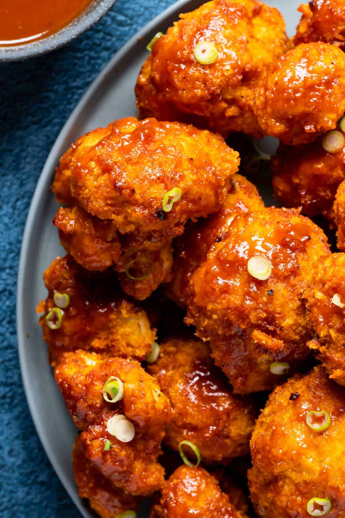 BBQ cauliflower wings on a plate with chopped spring onions.