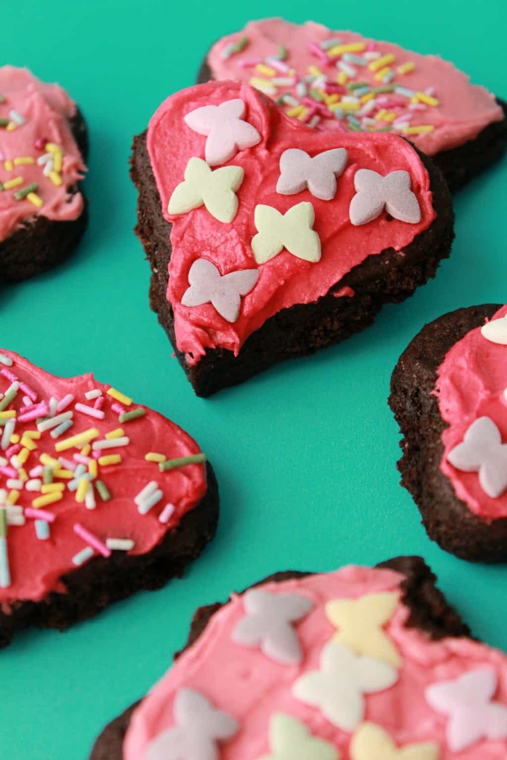Vegan chocolate sugar cookies with pink frosting and sprinkles. 
