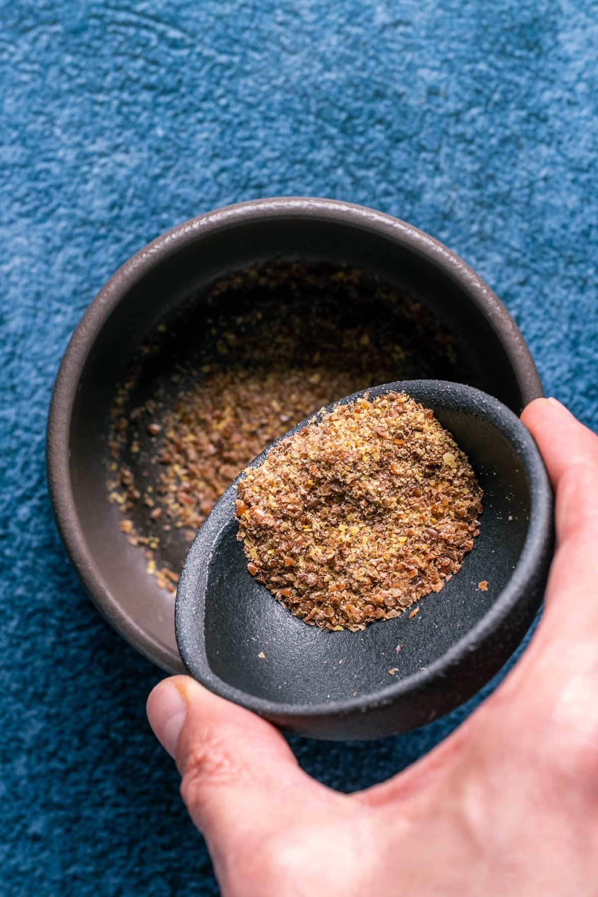 Photo of adding ground flaxseeds to a bowl.