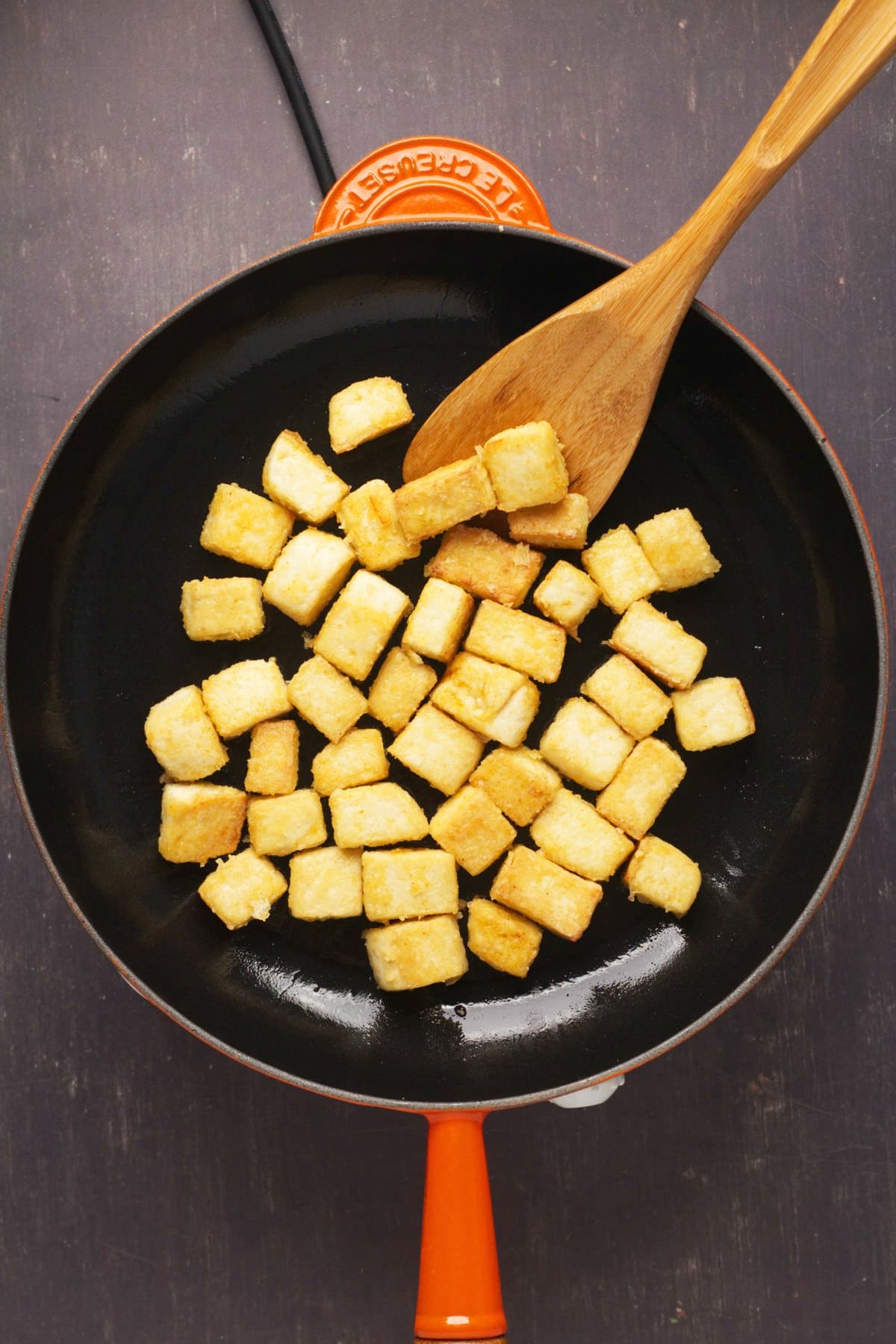 Cubes of tofu frying in a pan. 