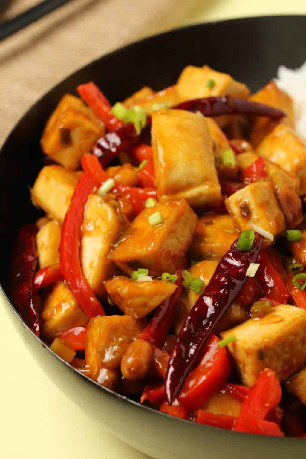 Kung pao tofu served in a wok topped with chopped spring onions. 