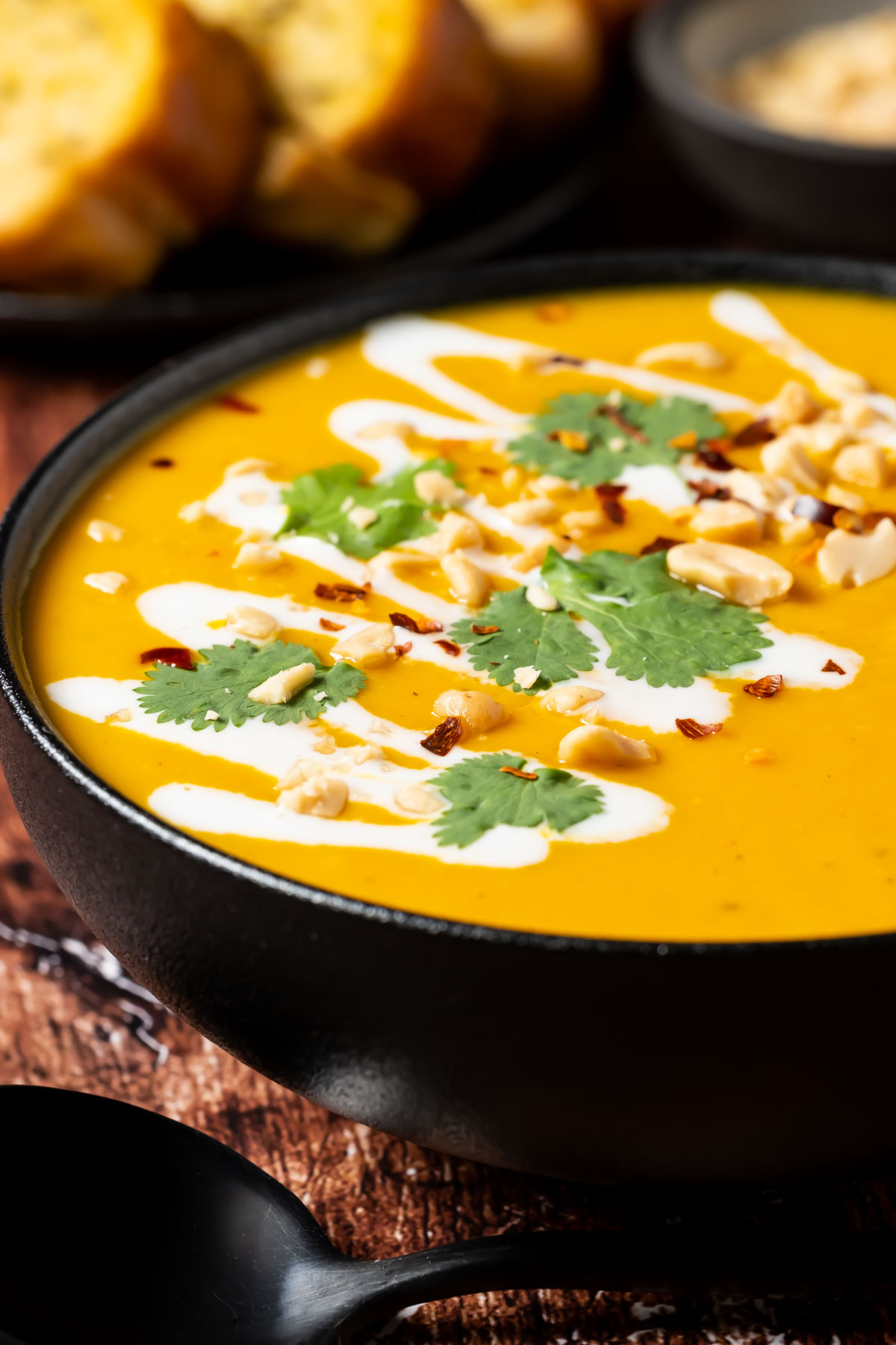 Thai butternut squash soup in a black bowl topped with crushed peanuts and fresh cilantro.