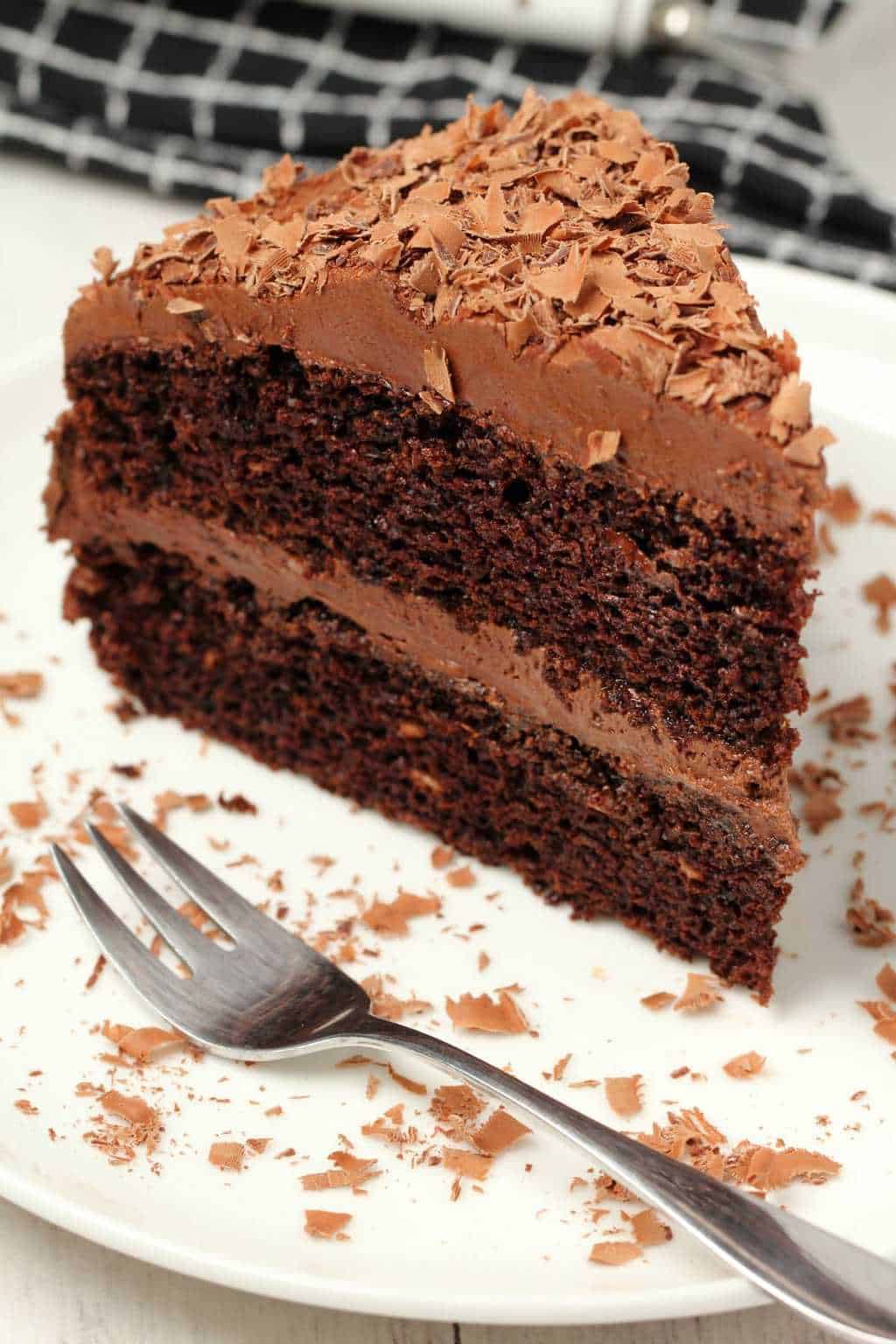 A slice of the chocolate cake on a white plate with a cake fork. 