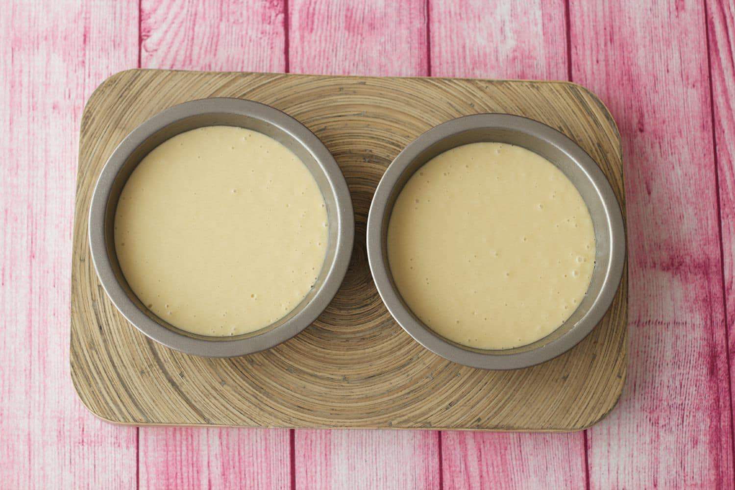 Vegan vanilla cake batter in two cake pans ready to go into the oven.