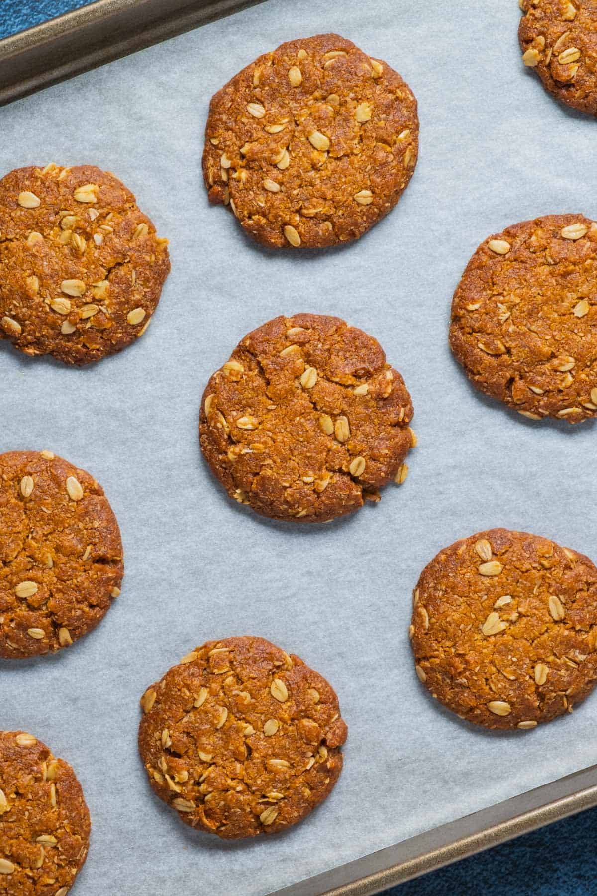 Vegan Anzac biscuits on a parchment lined baking tray.