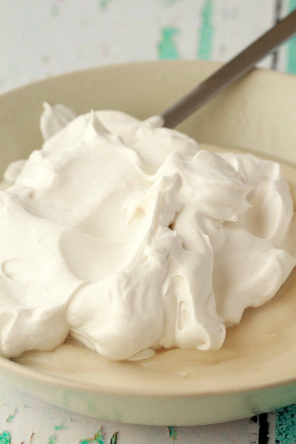 Adding vegan whipped cream to vanilla pudding in a bowl. 