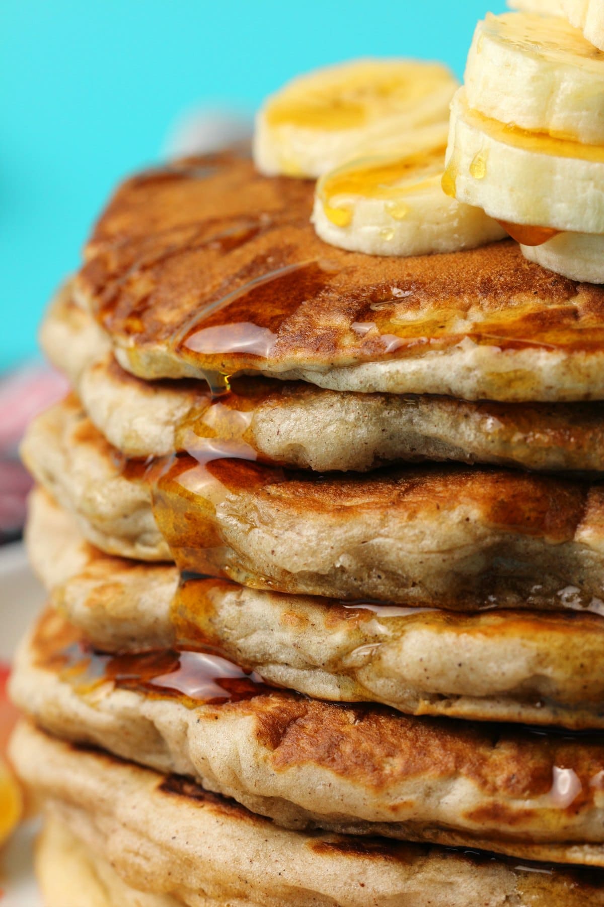 Stack of banana pancakes topped with sliced banana and syrup. 