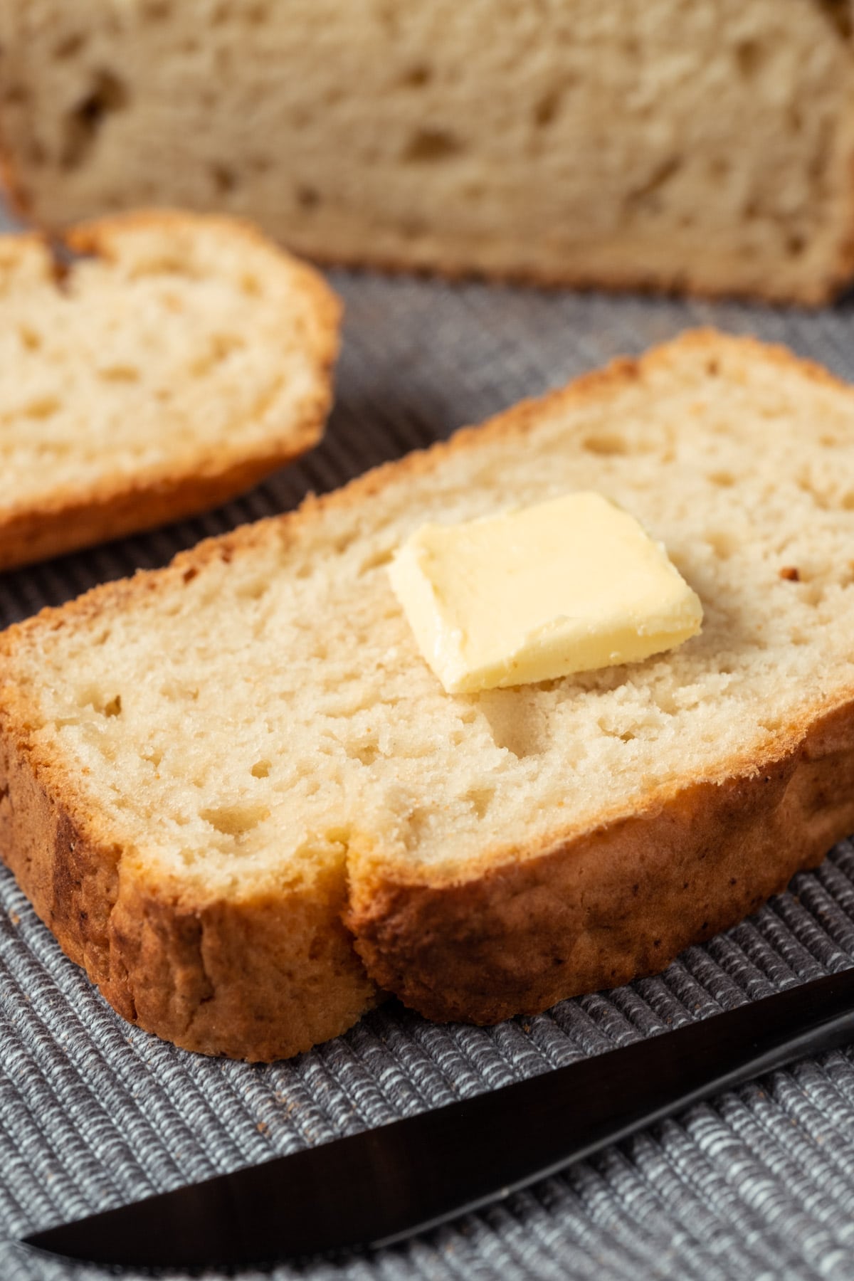 Slice of beer bread topped with a knob of vegan butter.