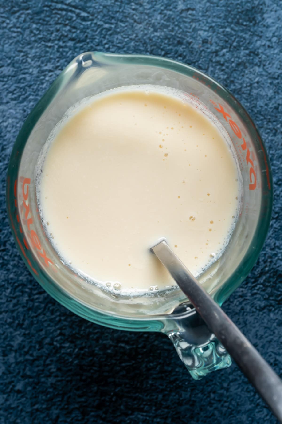 Vegan buttermilk in a glass jug with a spoon.