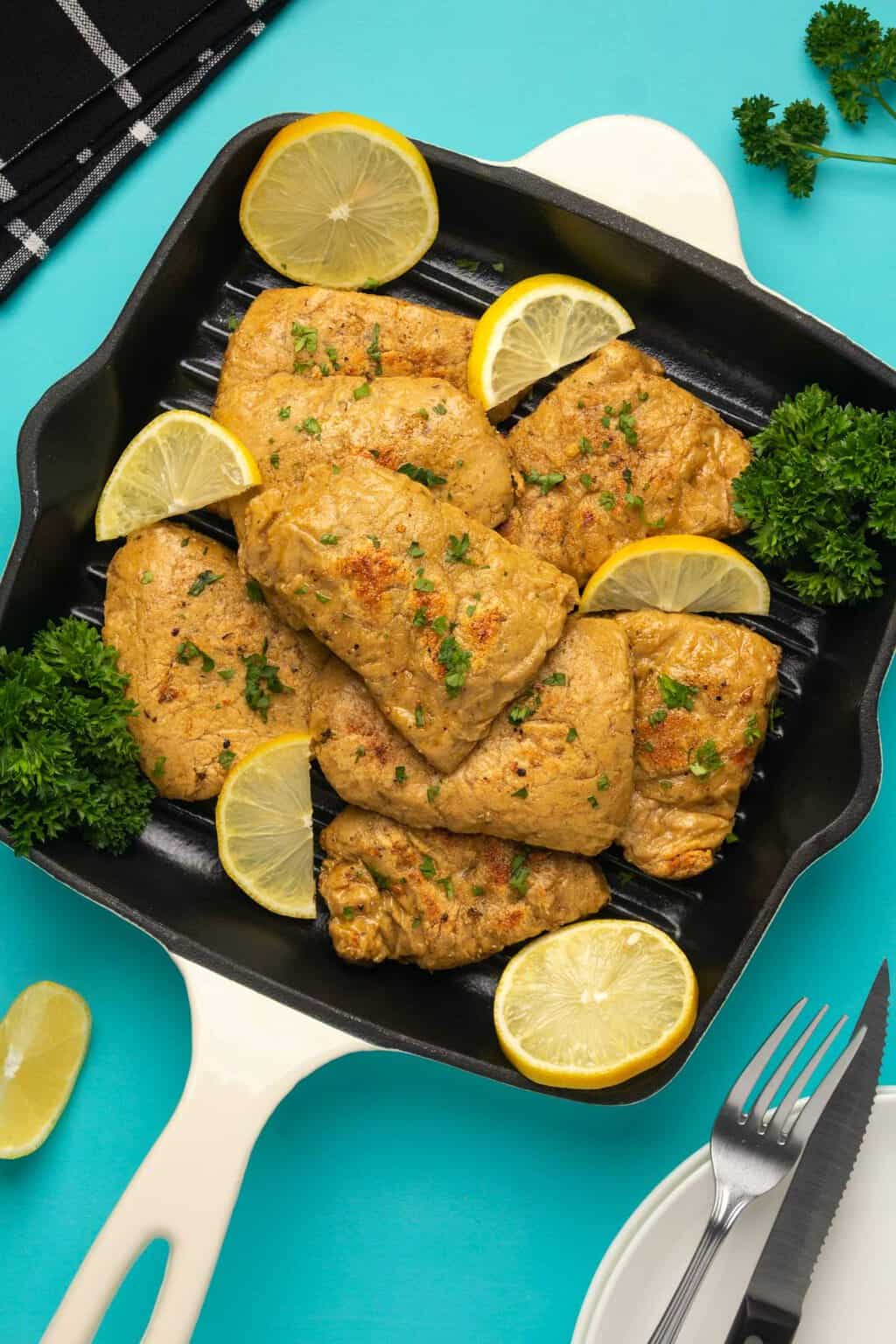 Vegan chicken fillets with fresh parsley and lemon slices in a frying pan. 