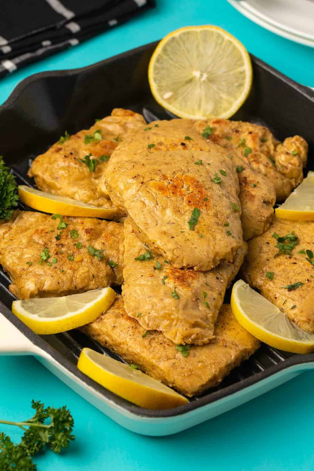 Vegan chicken fillets with chopped parsley and slices of lemon. 
