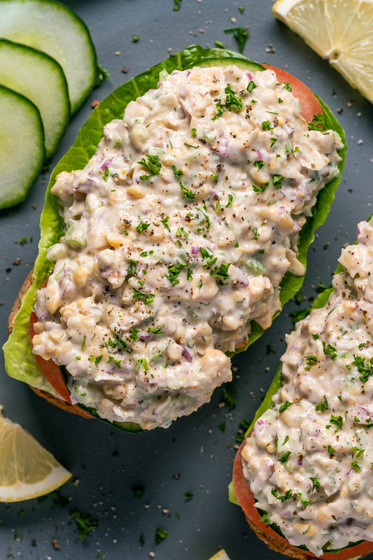 Open faced sandwiches topped with vegan chicken salad on a gray plate. 