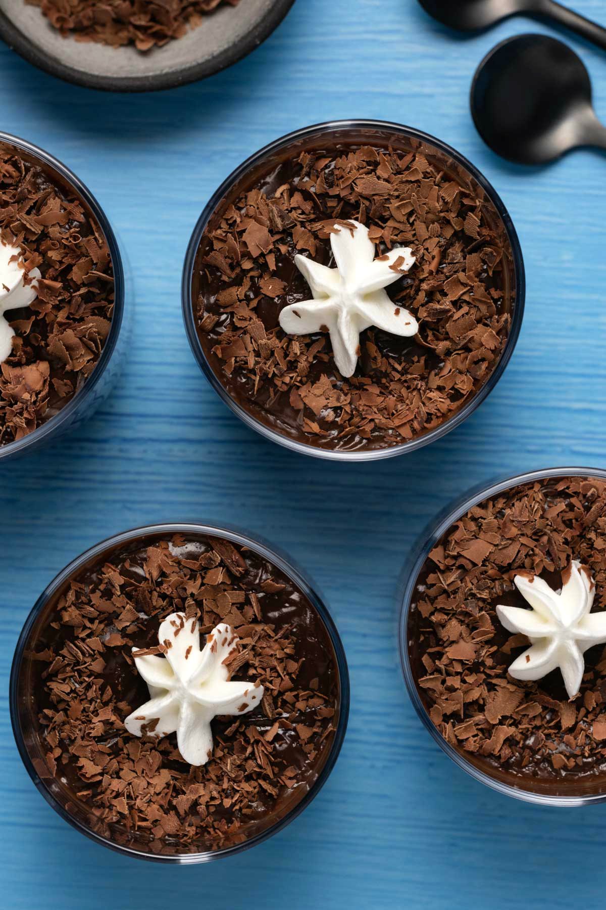 Vegan chocolate pudding in glasses topped with chocolate shavings and whipped cream. 