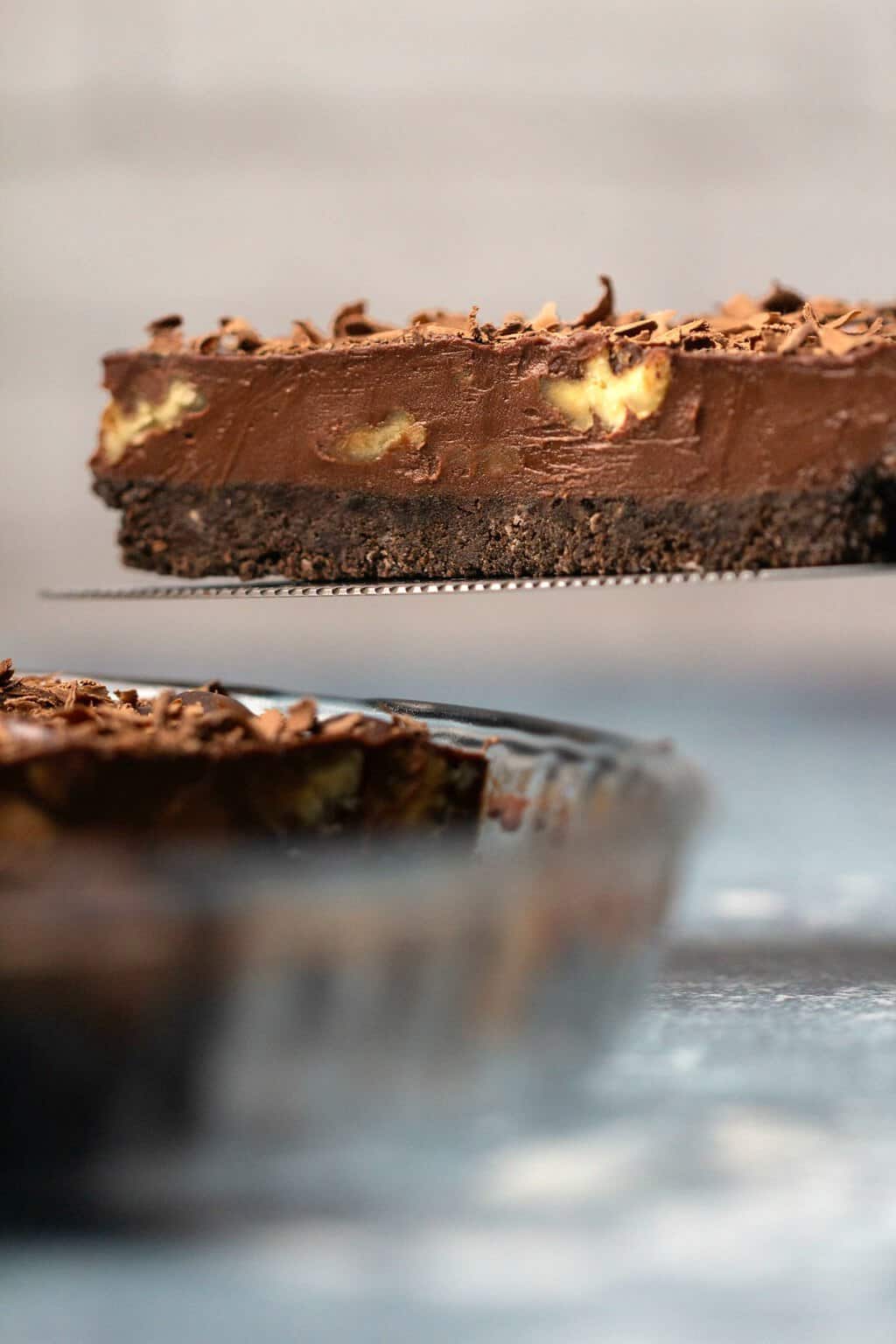 Slice of vegan chocolate tart on a cake lifter. 