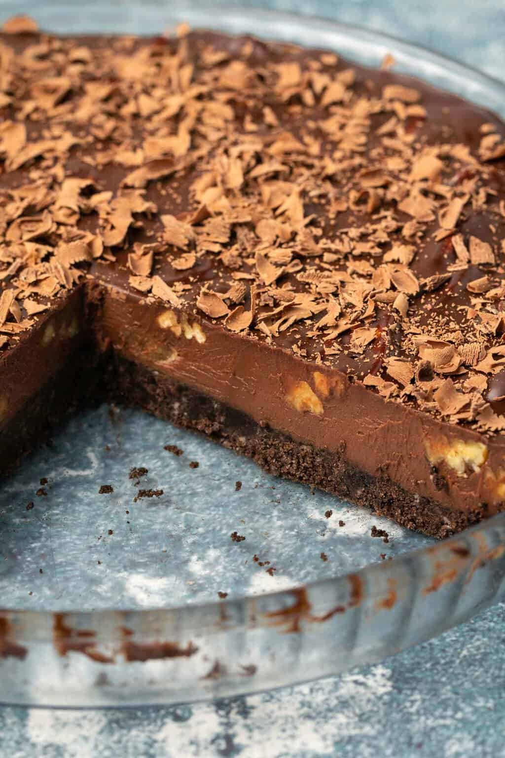 Vegan chocolate tart in a glass pie dish with one slice removed. 