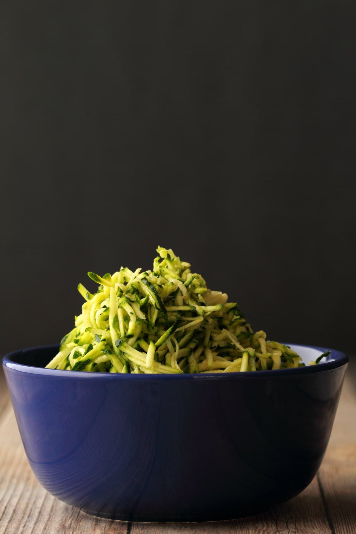 Grated zucchini in a blue bowl. 