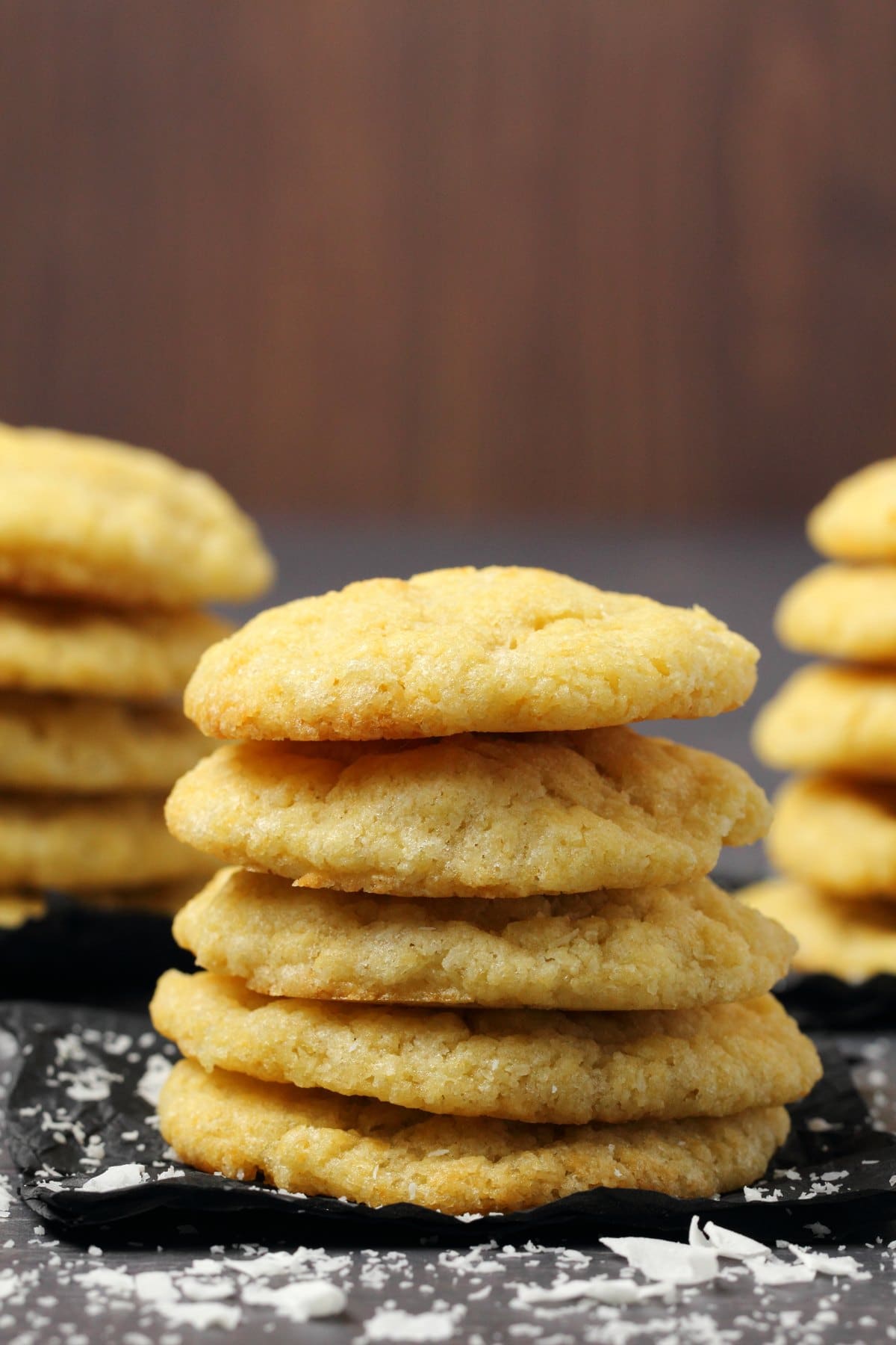 A stack of vegan coconut cookies on black tissue paper. 