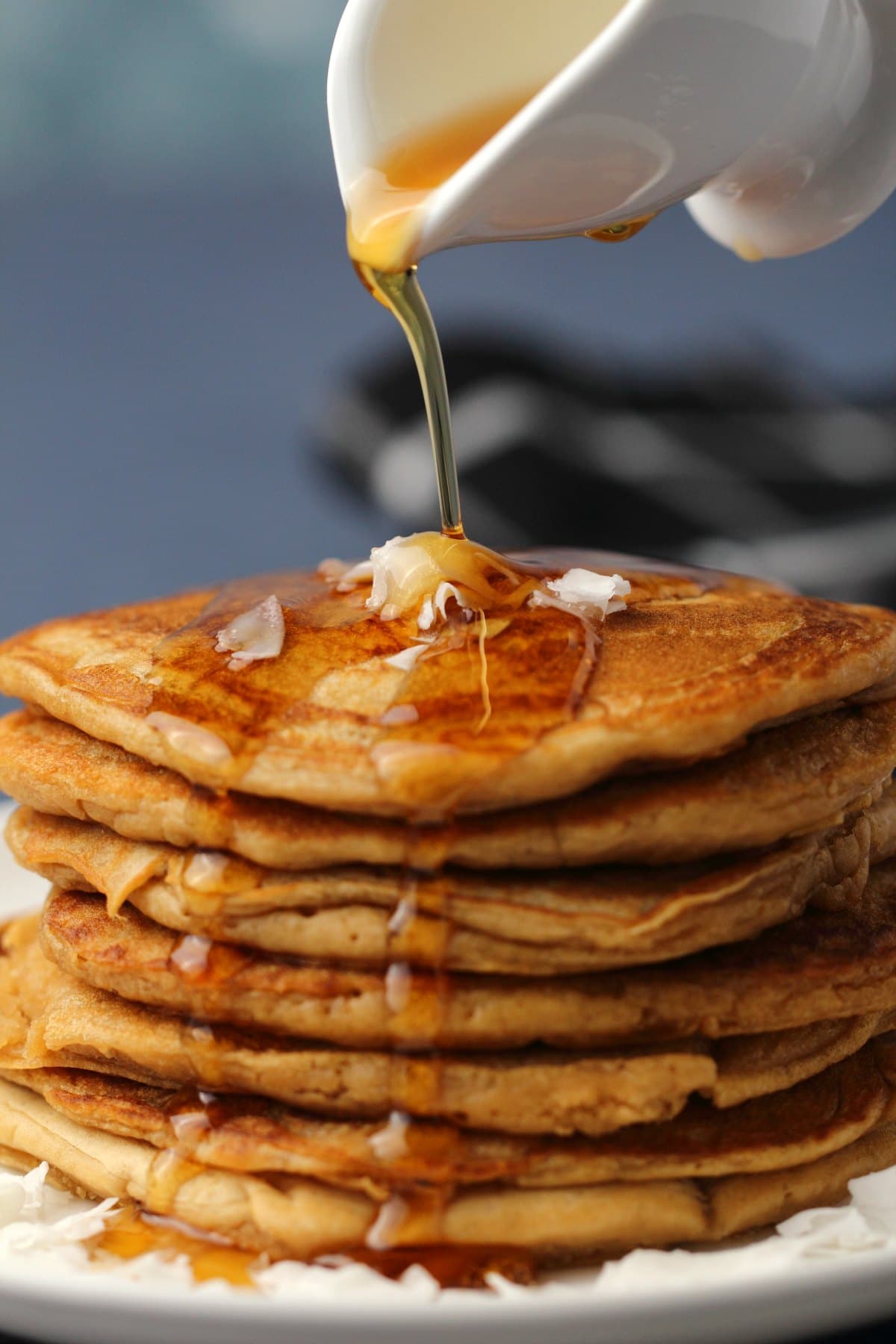 Syrup pouring over a stack of vegan coconut pancakes. 