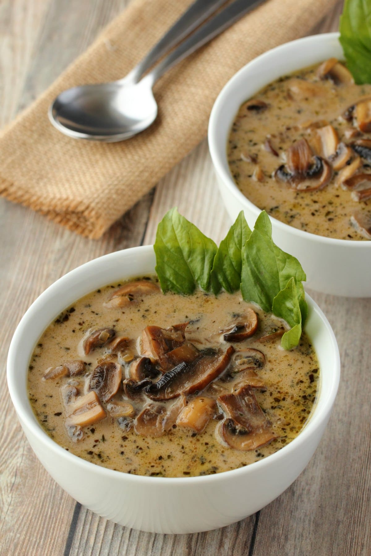 Vegan Cream of Mushroom Soup in a white bowl served with fresh basil.