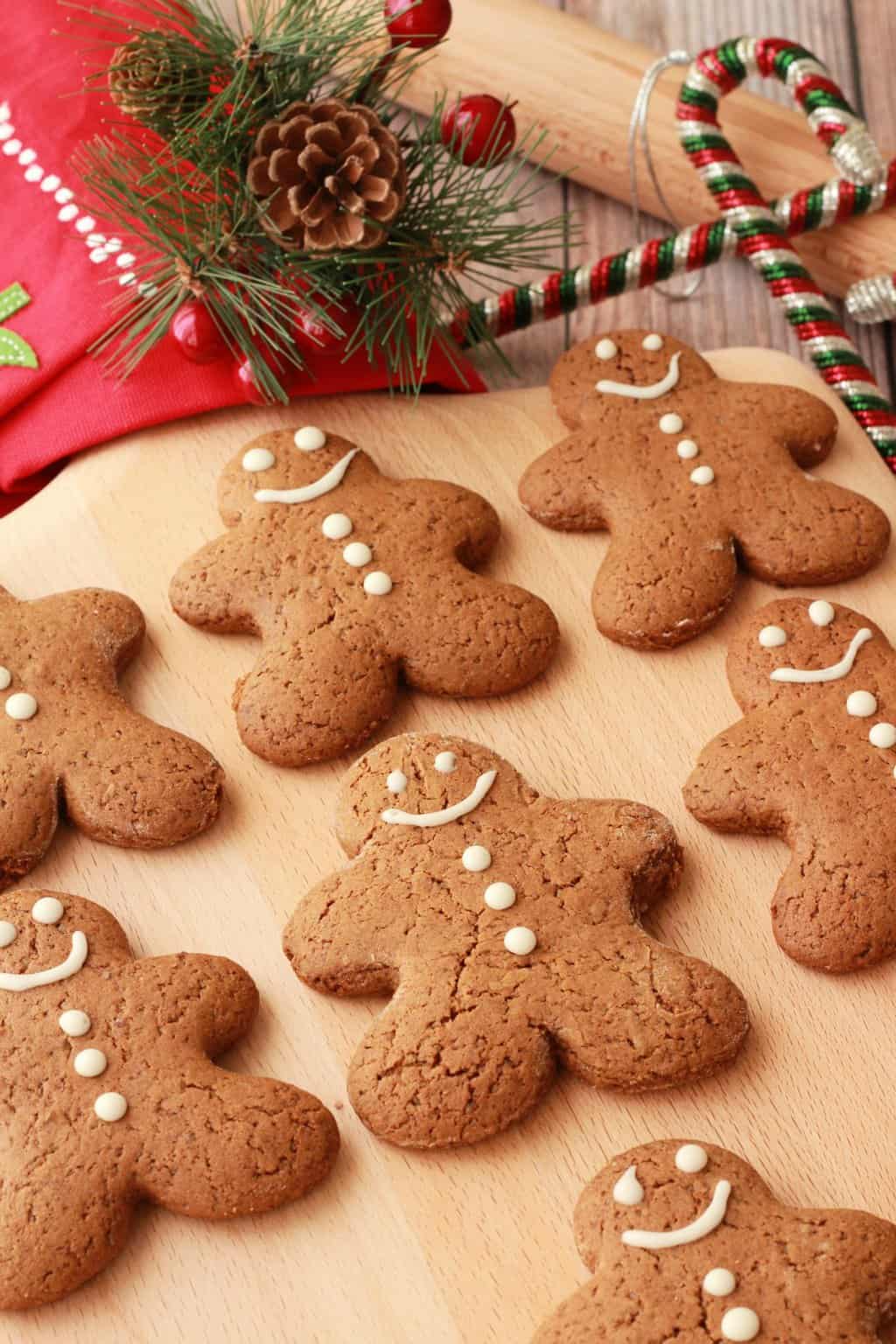 Vegan gingerbread cookies on a wooden board with Christmas decorations in the background. 