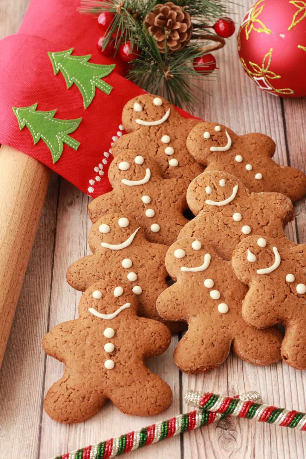 Vegan gingerbread cookies stacked up alongside Christmas decorations. 