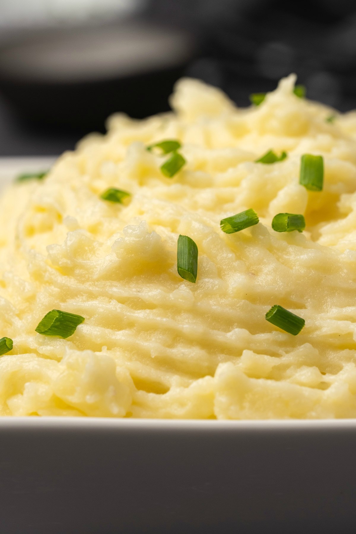 Vegan mashed potatoes with chopped chives in a white dish. 