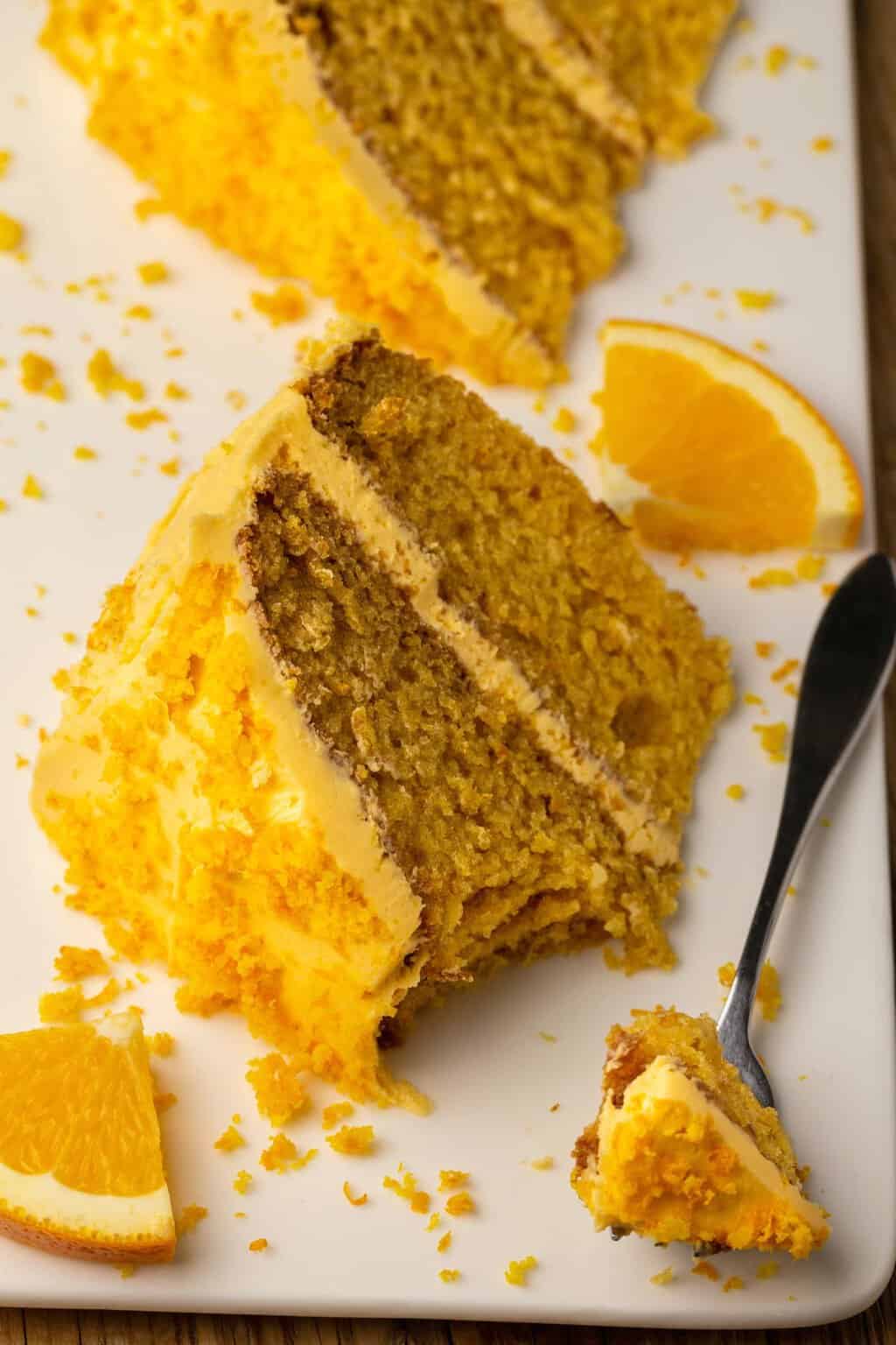 Slice of vegan orange cake on a white plate with a cake fork. 