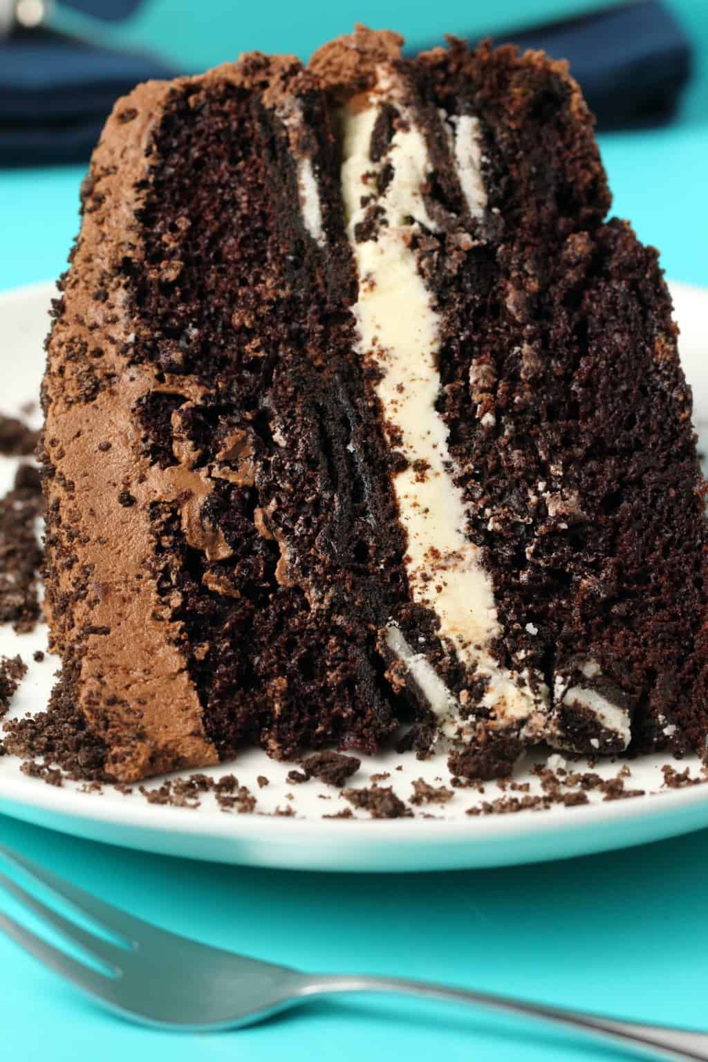 Slice of vegan oreo cake on a white plate with a cake fork. 