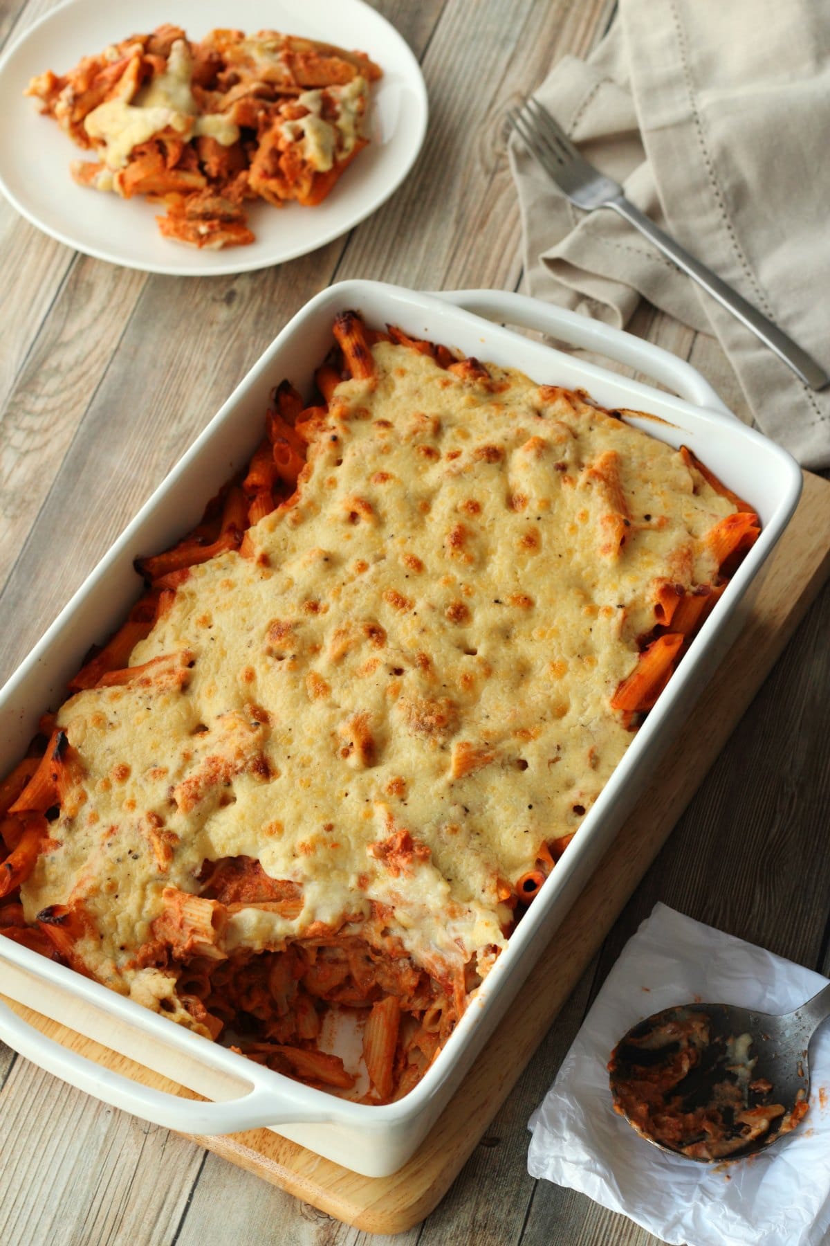 Vegan Pasta Bake in a white oven dish with a serving dished up on a white side plate. 