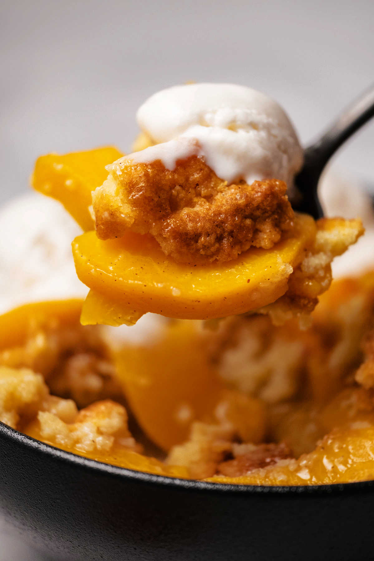 Spoonful of peach cobbler and ice cream. 