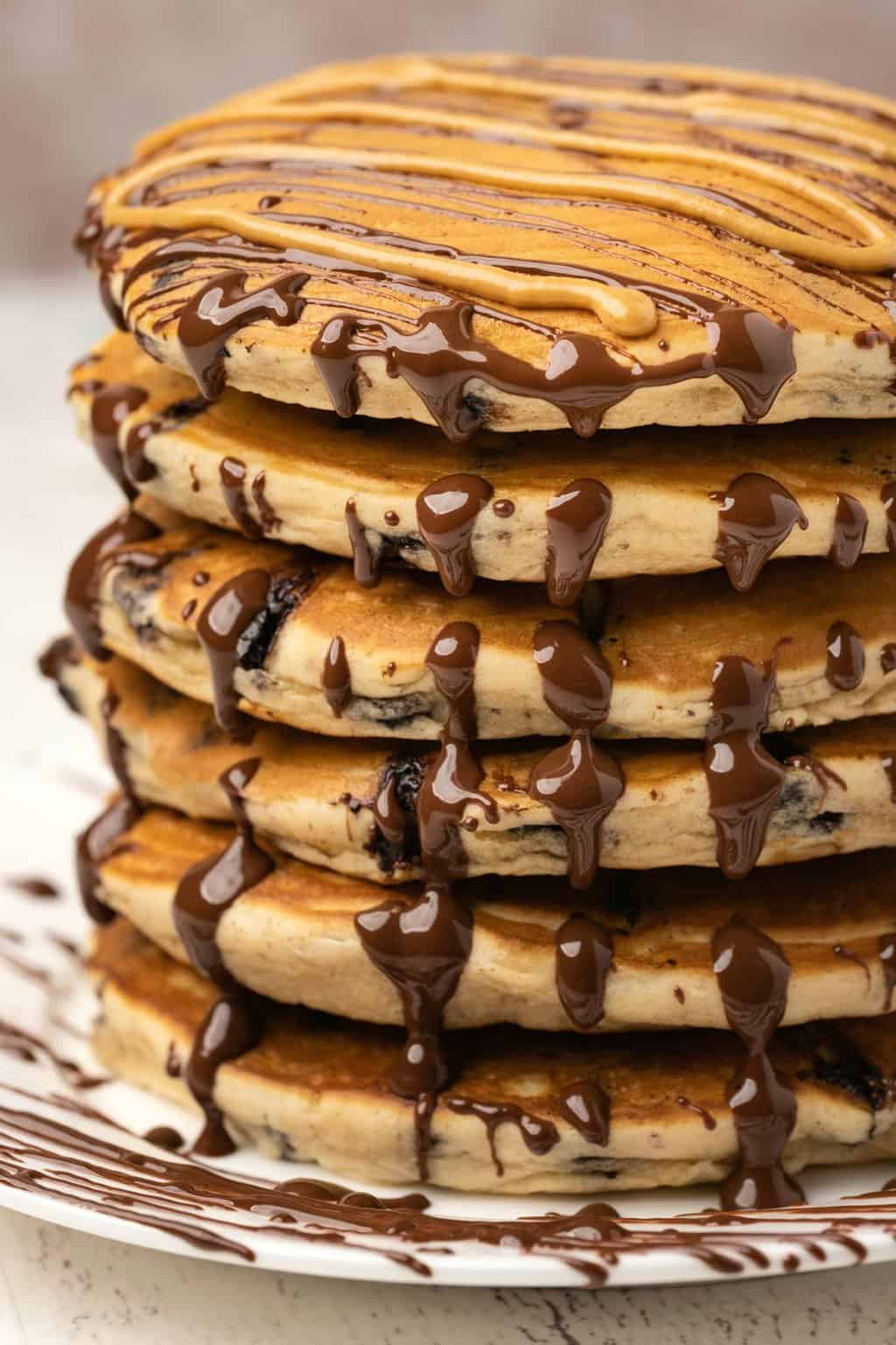 A stack of peanut butter pancakes drizzled with melted peanut butter and chocolate. 