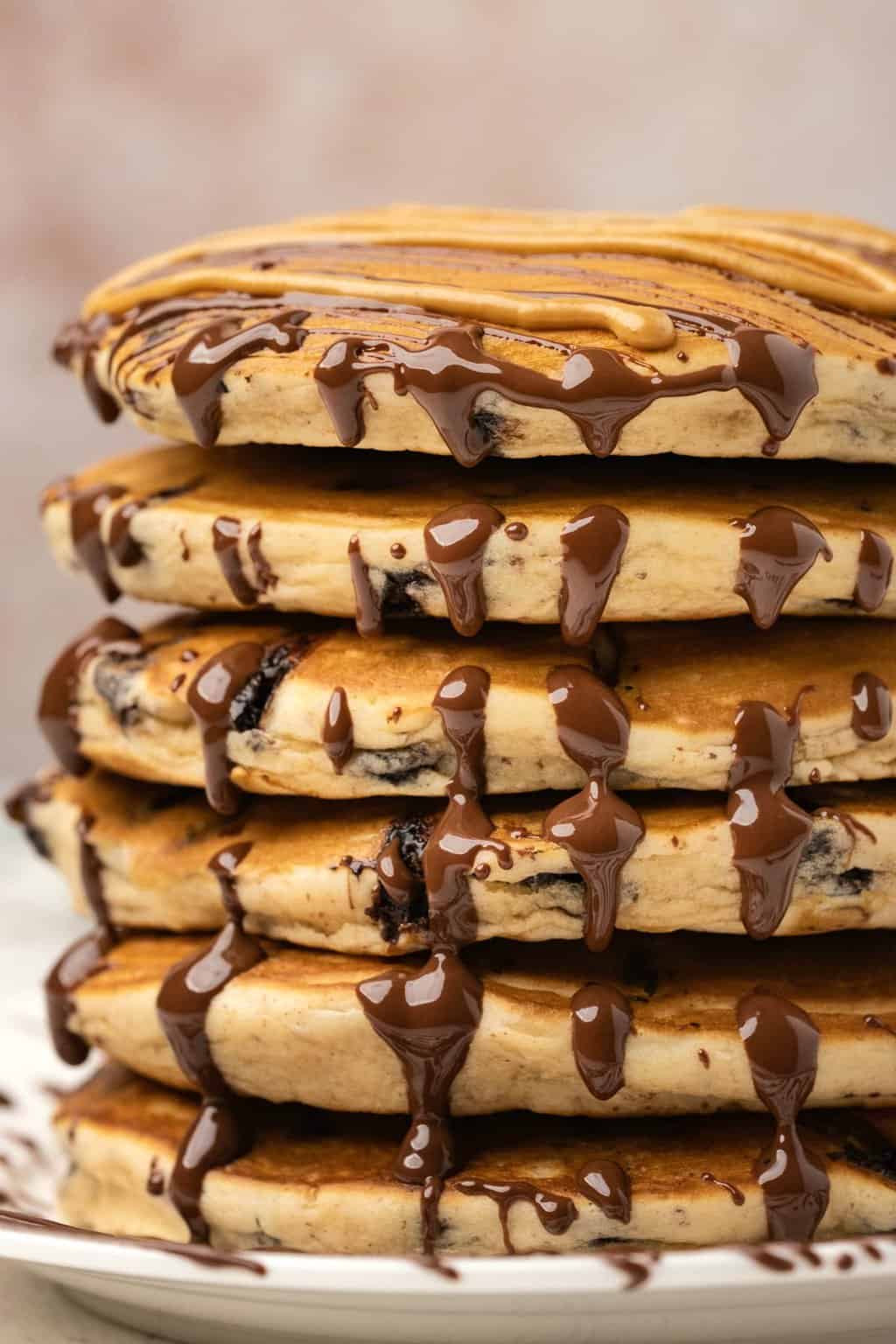 A stack of peanut butter pancakes with drizzled peanut butter and chocolate. 