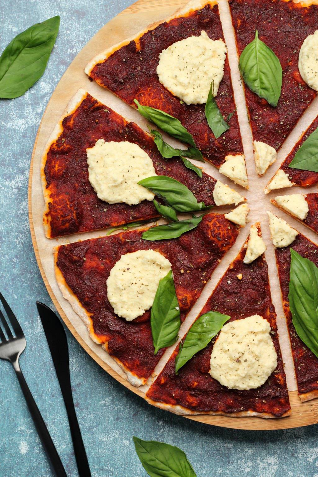 Vegan pizza topped with vegan ricotta and fresh basil leaves. 