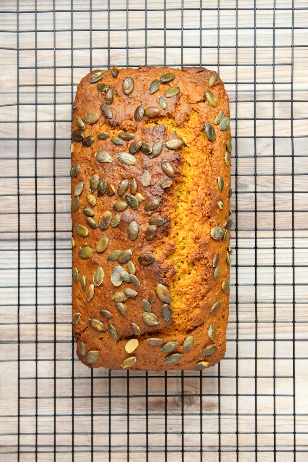 Loaf of vegan pumpkin bread on a wire cooling rack.