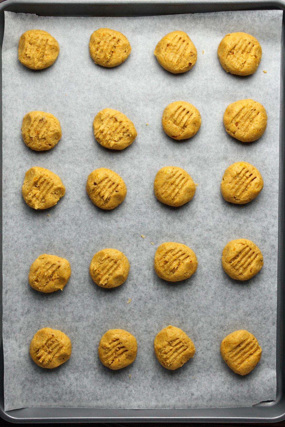 Pumpkin cookies on a parchment lined baking tray ready to go into the oven.