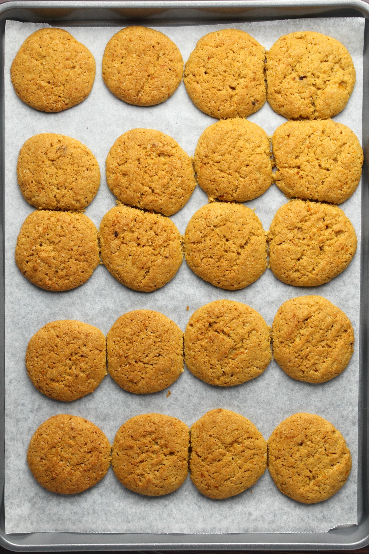 Freshly baked pumpkin cookies on a parchment lined baking tray.