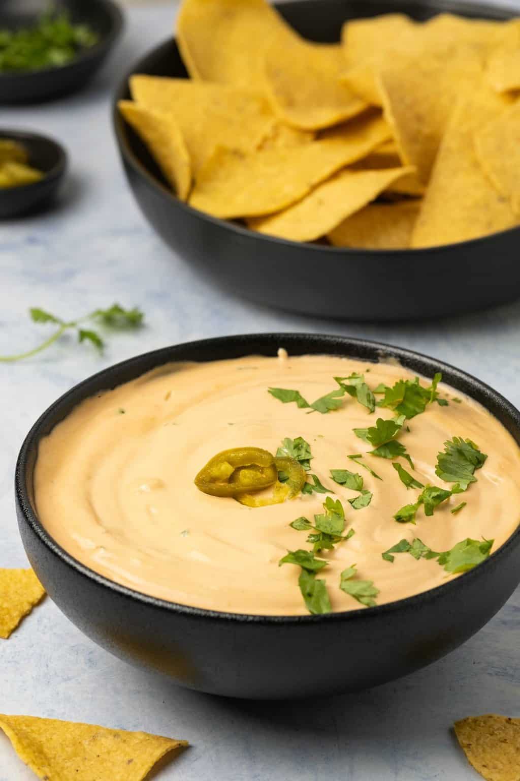 Vegan queso topped with sliced jalapeños and chopped cilantro. 