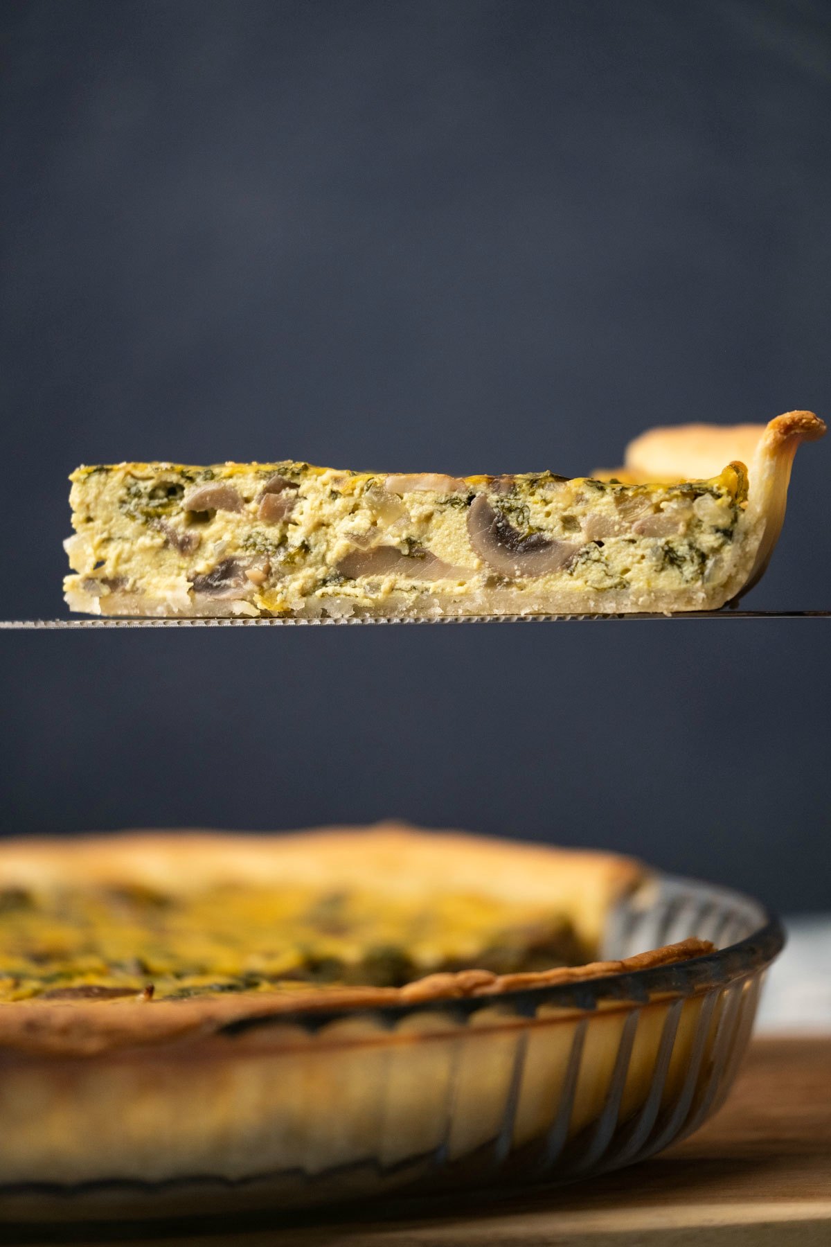 Slice of vegan quiche on a cake lifter. 
