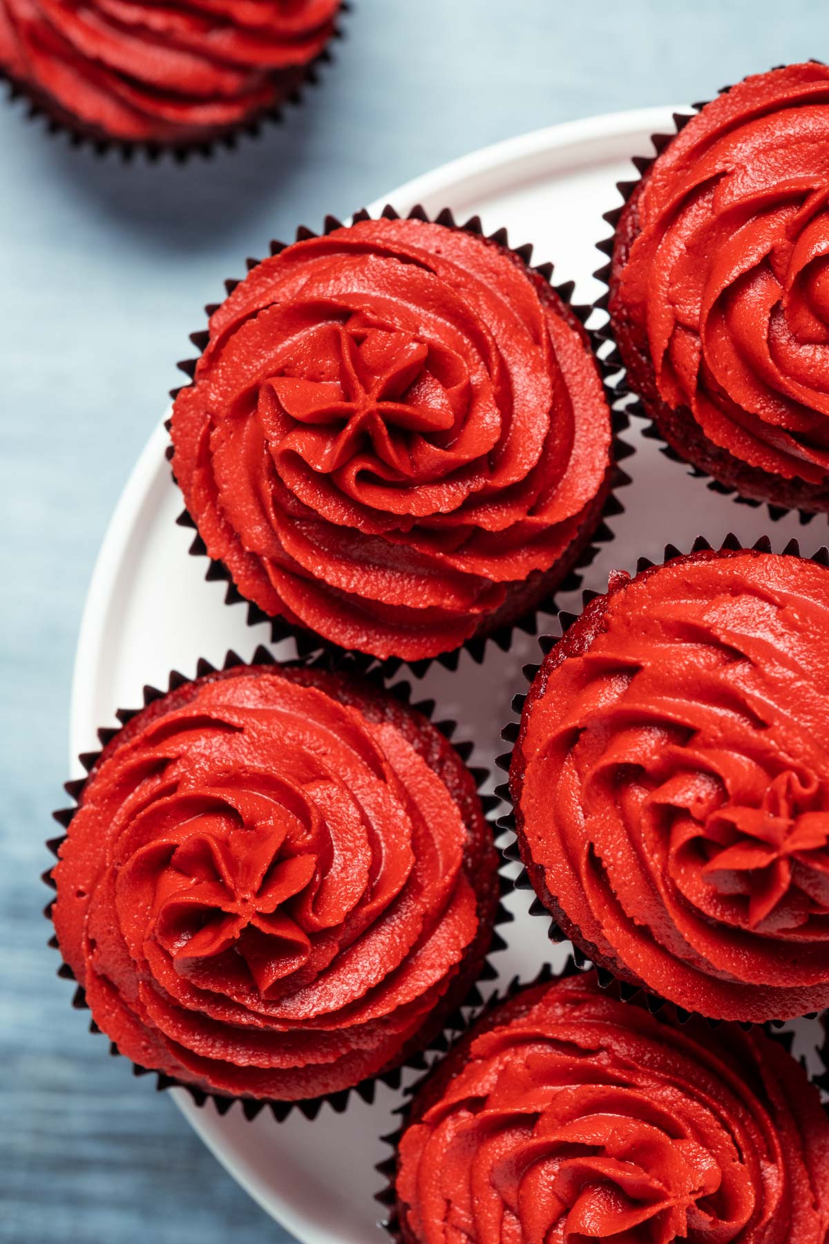 Vegan red velvet cupcakes on a white cake stand.