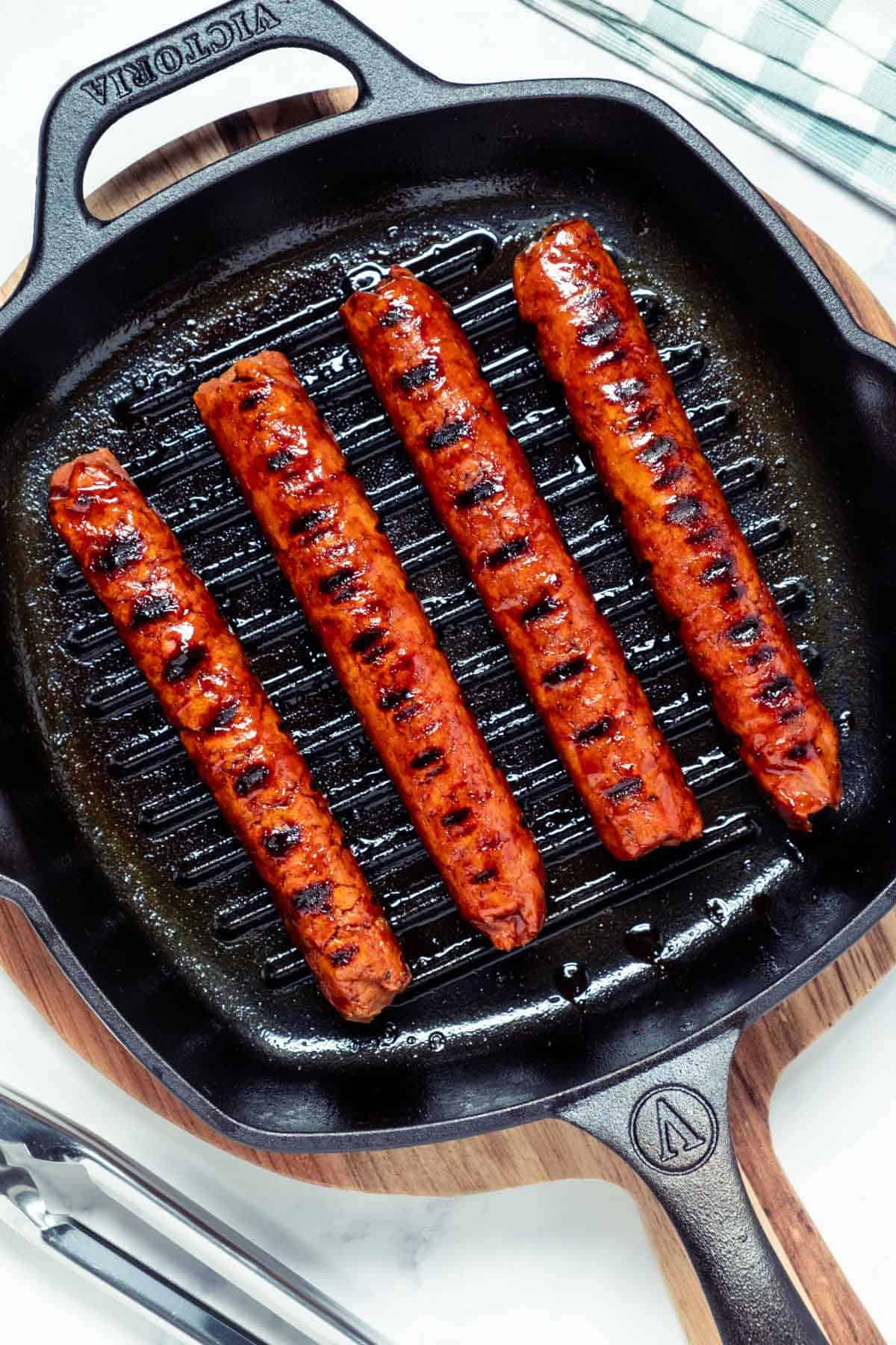 Photo of four vegan sausages in a grill pan.