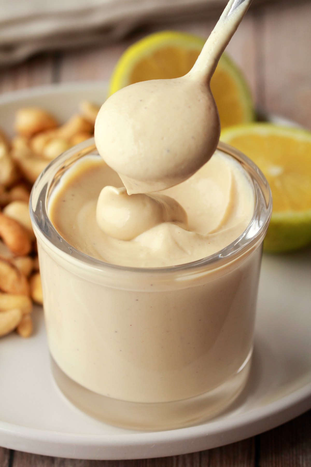 A spoon dipping into a glass jar full of vegan sour cream. 