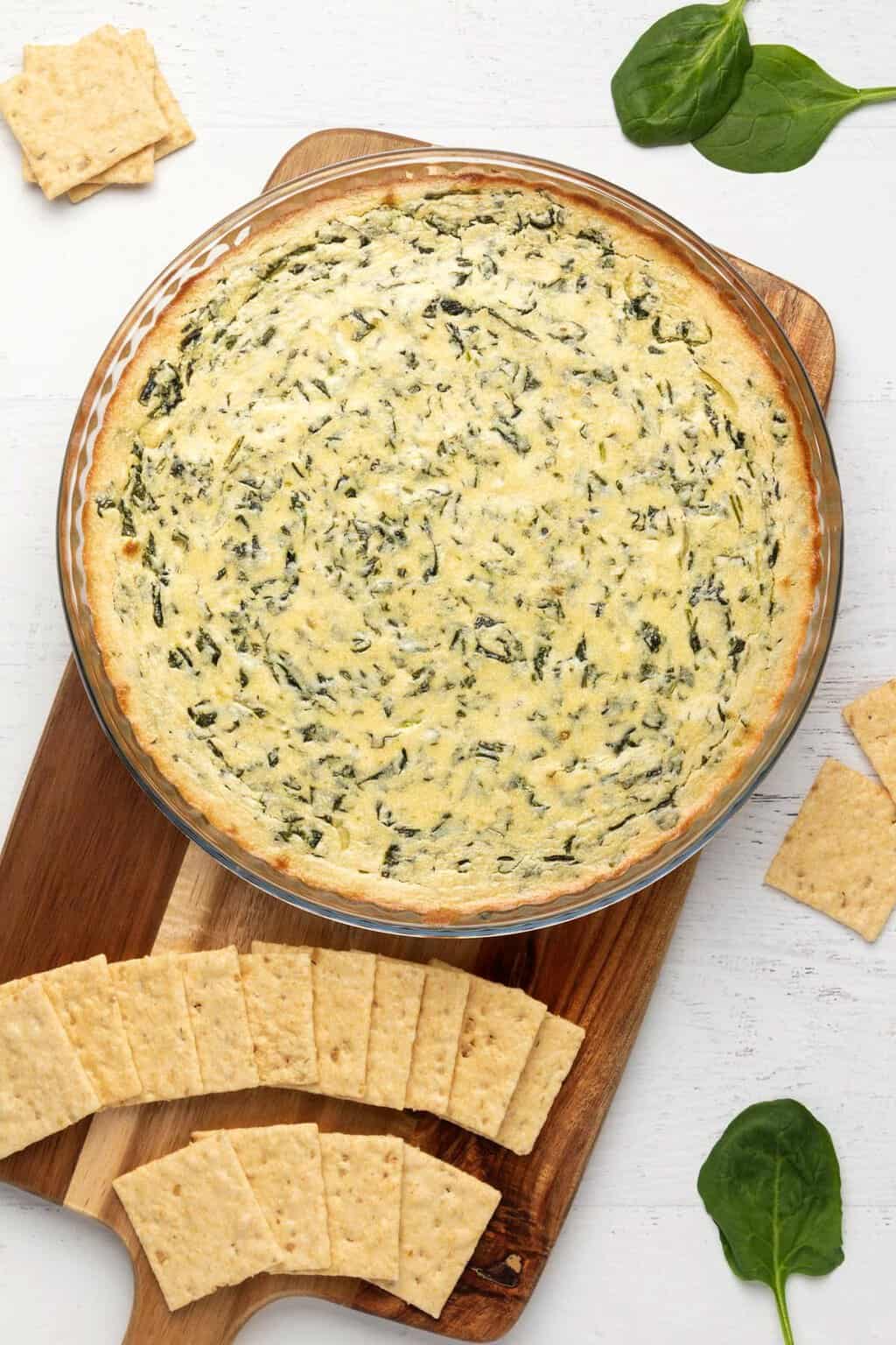Freshly baked vegan spinach dip in a round glass dish. 