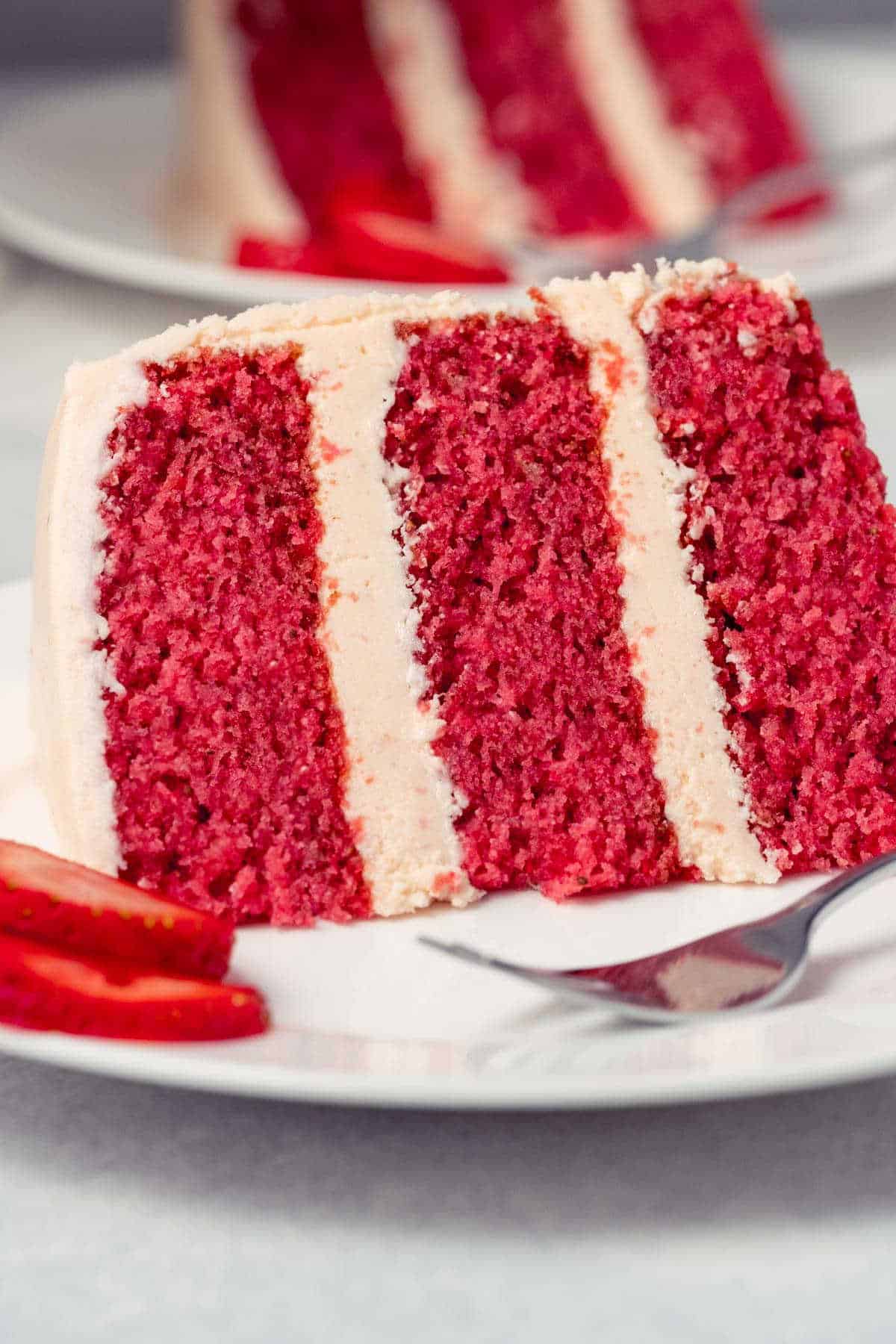 Slice of strawberry cake on a white plate with a cake fork.