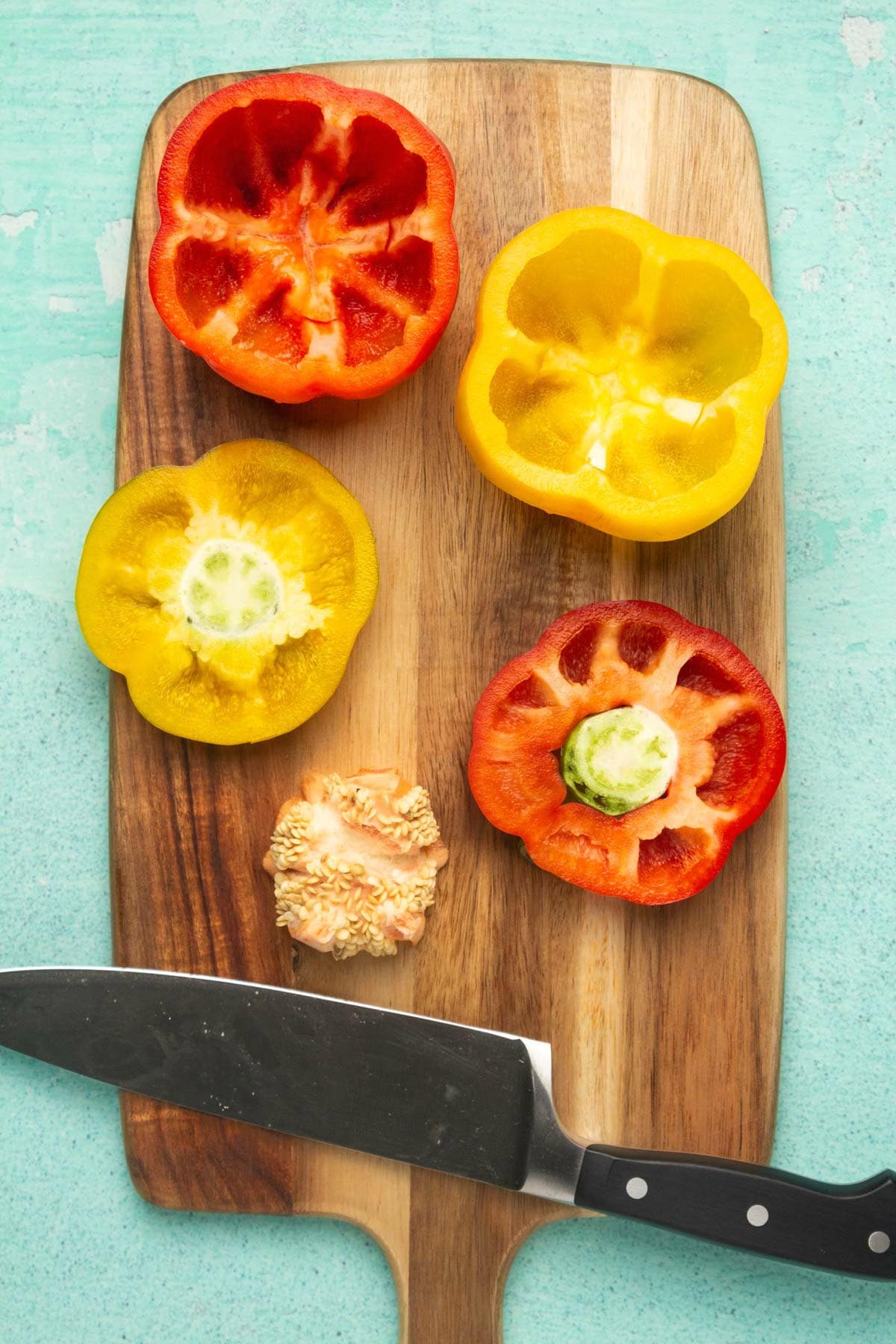 Cored bell peppers on a wooden cutting board.