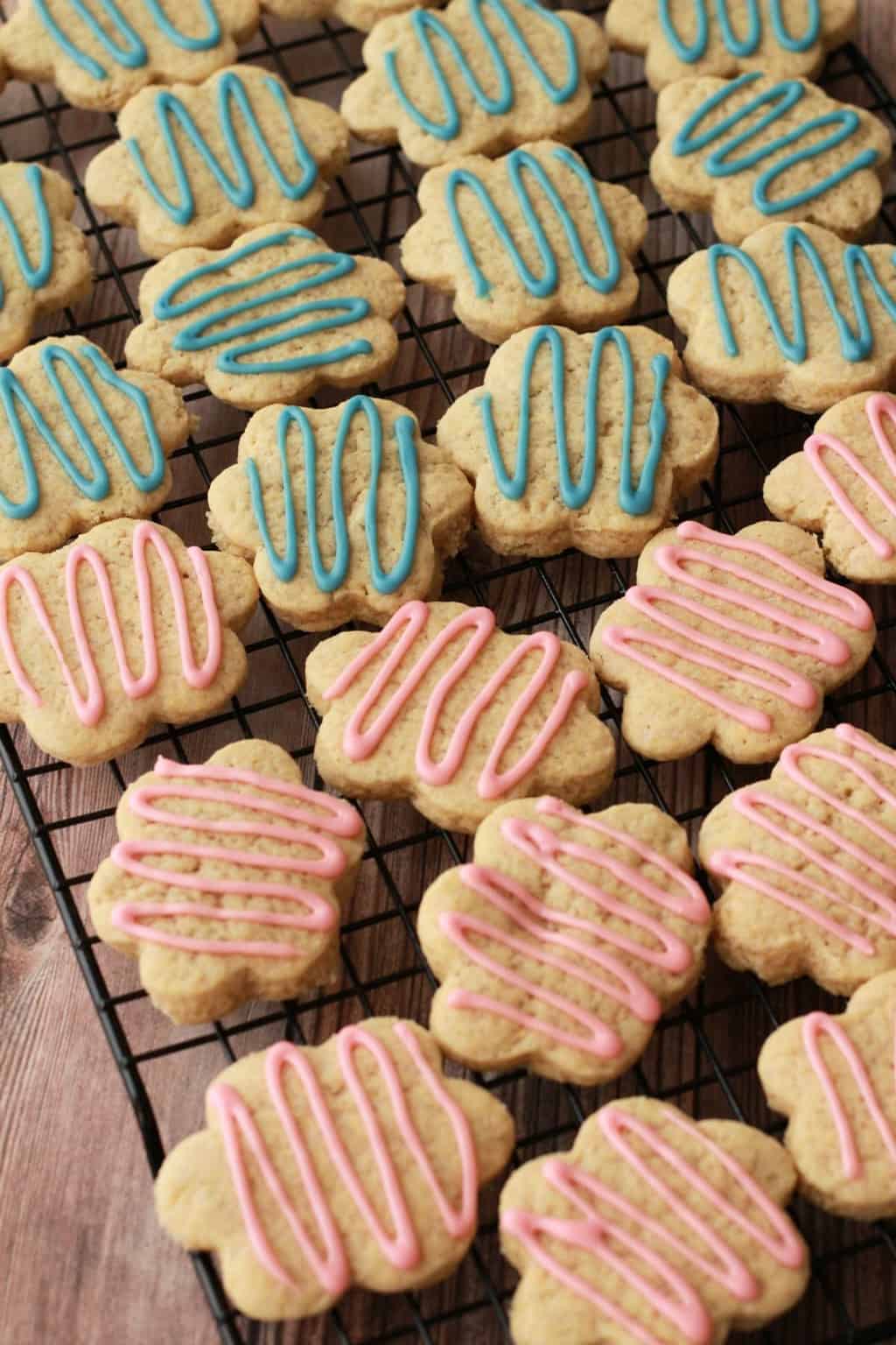 Vegan sugar cookies drizzled with pink and blue frosting on a wire cooling rack. 
