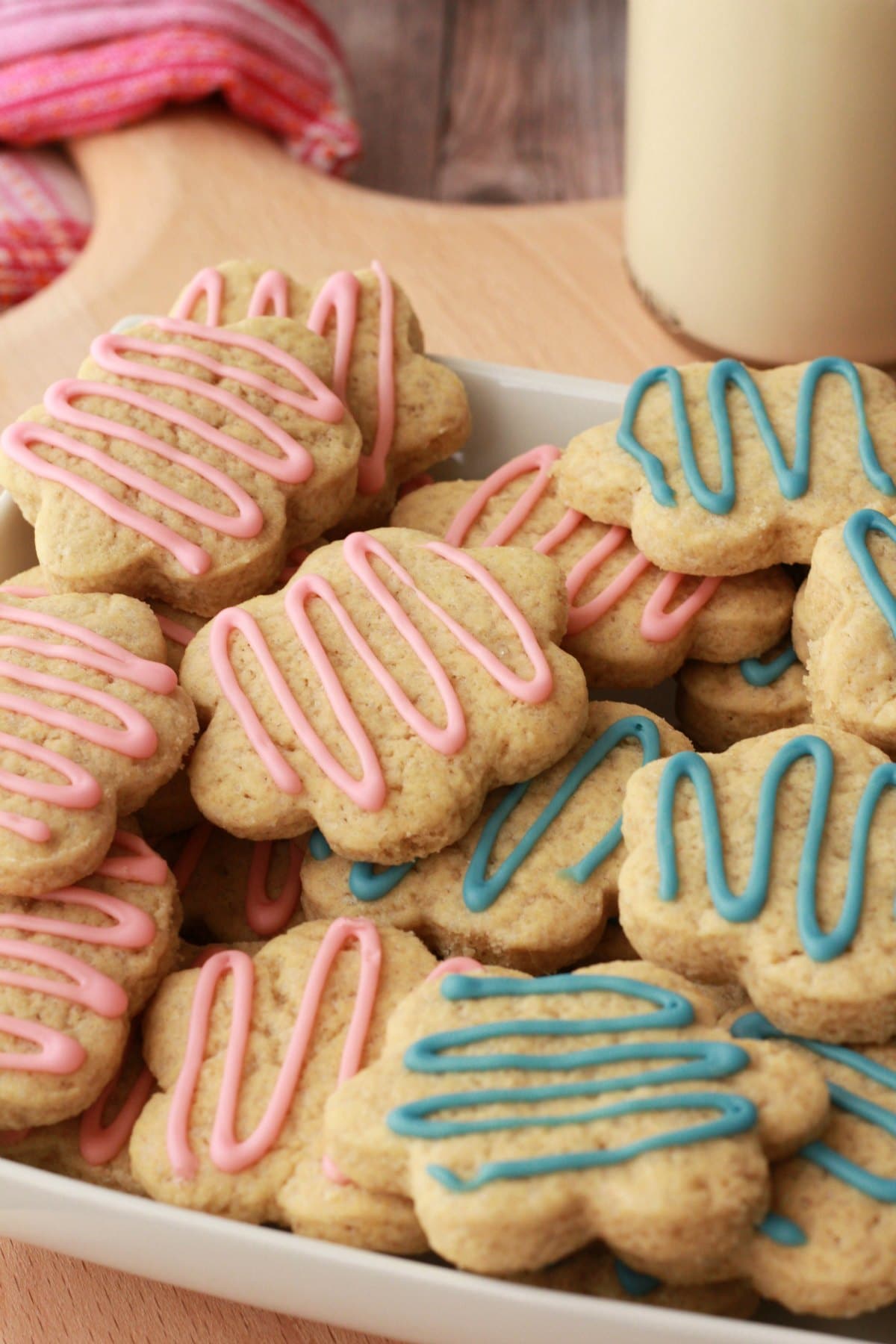 Vegan sugar cookies drizzled with pink and blue frosting in a white dish. 