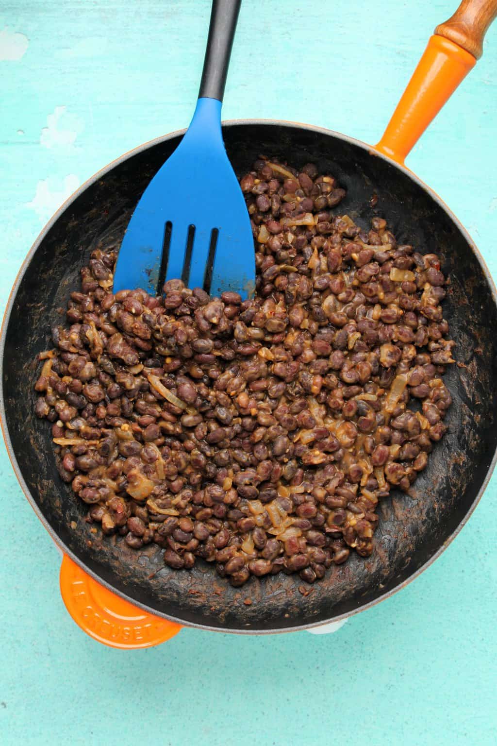 Black beans for vegan tacos, with onions and spices mixed up in a frying pan. 