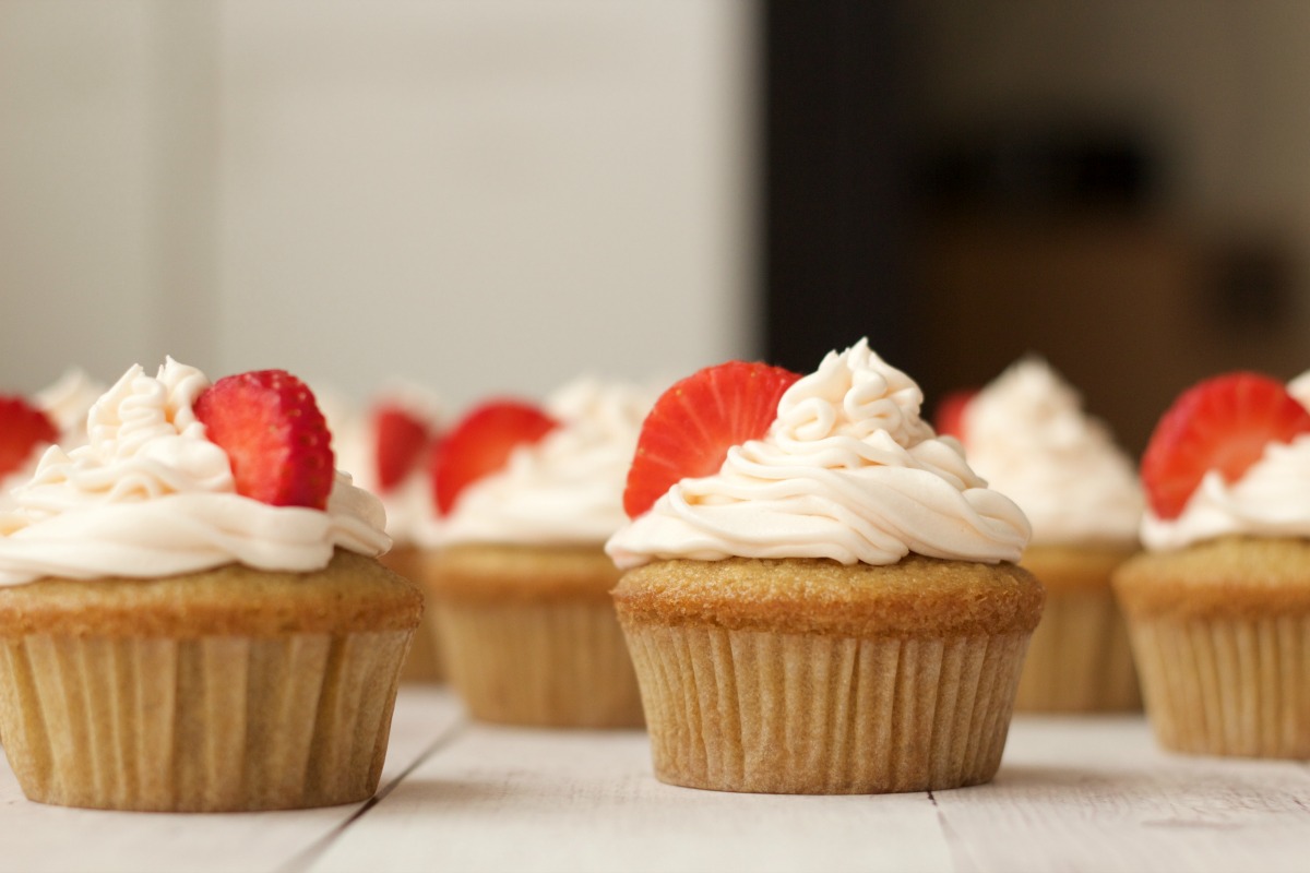 Vegan vanilla cupcakes with strawberry vanilla frosting and fresh strawberry decoration.