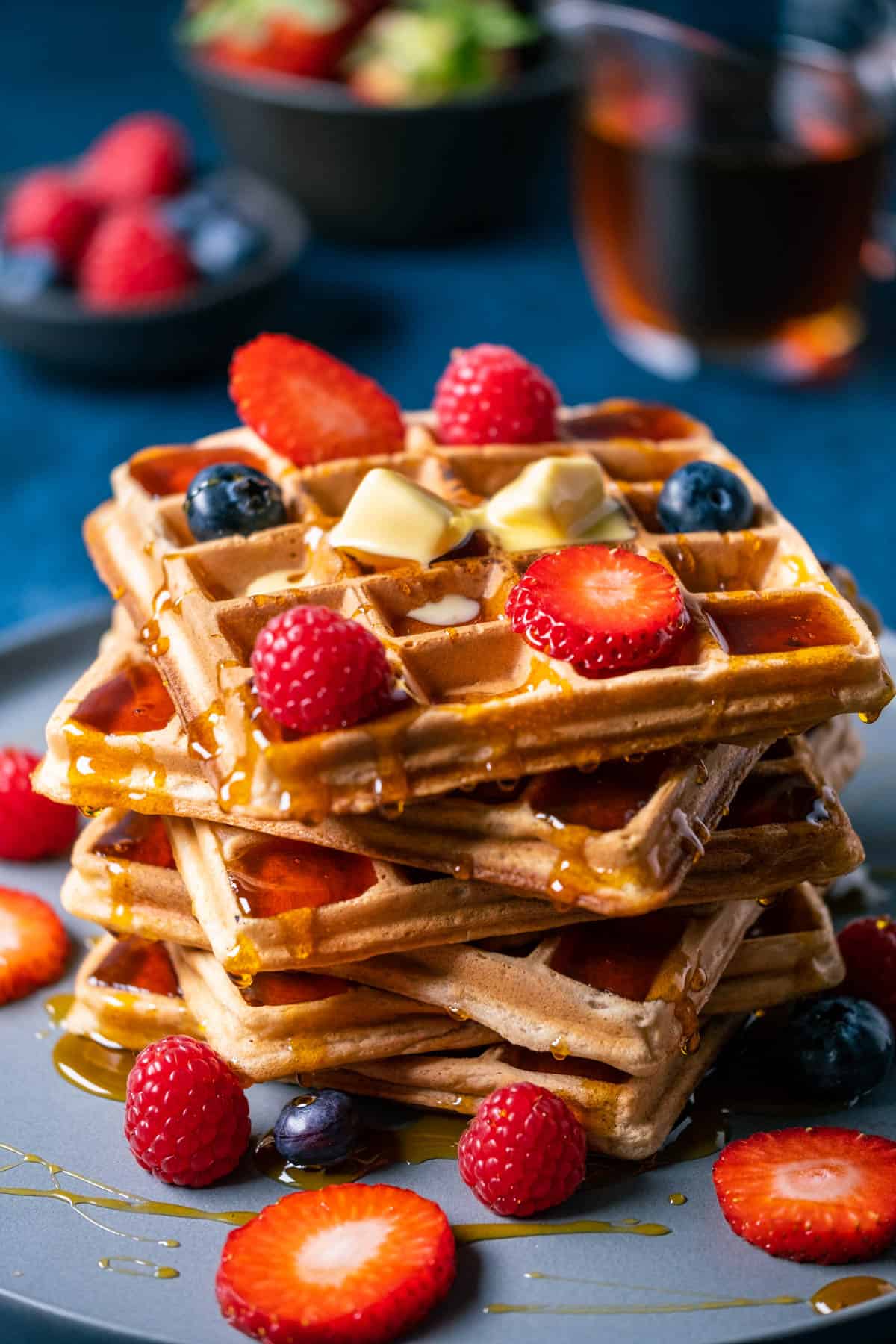 Stack of wafles topped with butter and fresh berries.
